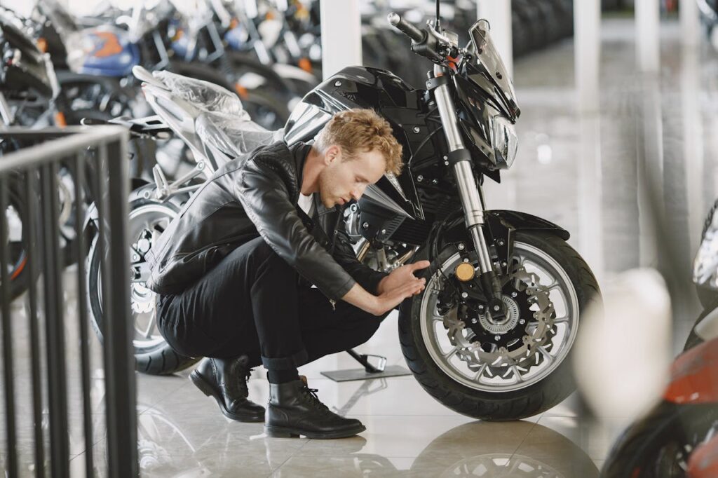 pexels-photo-5622320 Stylish man inspecting motorcycle tire in a showroom wearing a black leather jacket.